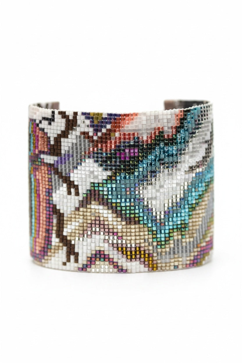 The JULIE ROFMAN - TAHITI CUFF by JULIE ROFMAN JEWELRY is a handwoven bracelet featuring multicolored beads in an abstract pattern. It showcases vibrant hues of blue, pink, gold, black, and white. The intricate design is crafted from small square beads and colorful agates, giving it a beautifully textured and artistic appearance.