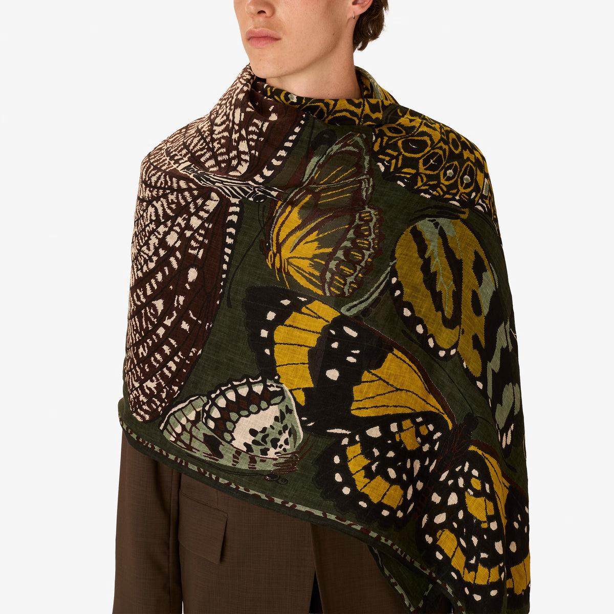 The INOUI EDITIONS - PAPILLONS SCARF IN KHAKI by INOUI is a rectangular linen scarf hand-printed with yellow, white, green, and black butterflies on a dark green background—perfect for elevating your khaki scarf collection.