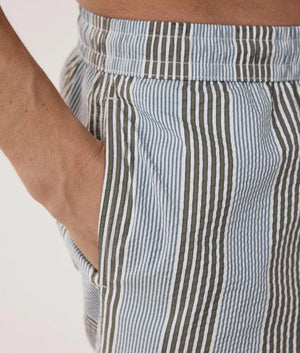 HARTFORD Seersucker Swim Trunks in green and blue stripes for men feature an elastic waistband, white drawstring, and olive accents. These mid-length swim shorts offer a classic look in textured seersucker fabric, shown on a light background.
