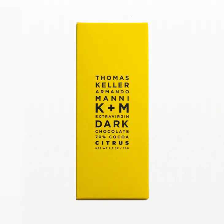 A yellow rectangular chocolate bar package with the text &quot;K &amp; M Extravirgin Chocolate K+M Extravirgin Dark Chocolate Citrus Bar 70% Cocoa Single-Origin Hacienda Victoria Estate Net Wt. 2.5 oz / 70g&quot; printed in black in the center.