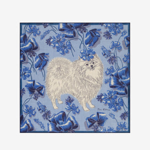 A close-up of the INOUI EDITIONS TOUTOU DOGGIE Wool Scarf in Blue shows its soft, woven texture and abstract blue, beige, and navy patterns. This 70x70cm INOUI accessory is gently twisted to highlight its intricate design—perfect for any wardrobe.