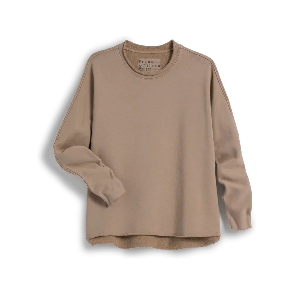 A woman with long brown hair stands indoors, her back to the camera, wearing the FRANK &amp; EILEEN Anne Long Sleeve Capelet in beige and white pants near a wooden staircase and dining area with chairs.