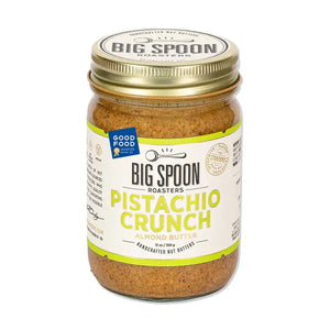 A jar of Big Spoon Roasters Pistachio & Almond Crunch Nut Butter. The jar features a gold lid and a white label with green text. A blue "Good Food Awards" badge is visible on the label, highlighting its use of heirloom mission almonds. The vegan nut butter boasts a crunchy texture.