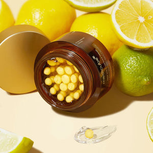The GLOWISS MEDICUBE DEEP VITA C CAPSULE CREAM, shown in an open jar with yellow capsules on a yellow background and surrounded by lemons, features sea buckthorn, niacinamide, and ascorbic acid to brighten and even skin tone.