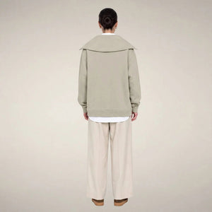 A woman wears a sleek rainy beige SAVE THE DUCK - HINATA HALF ZIP TOP with a wide collar and matching wide-leg drawstring sweatpants.