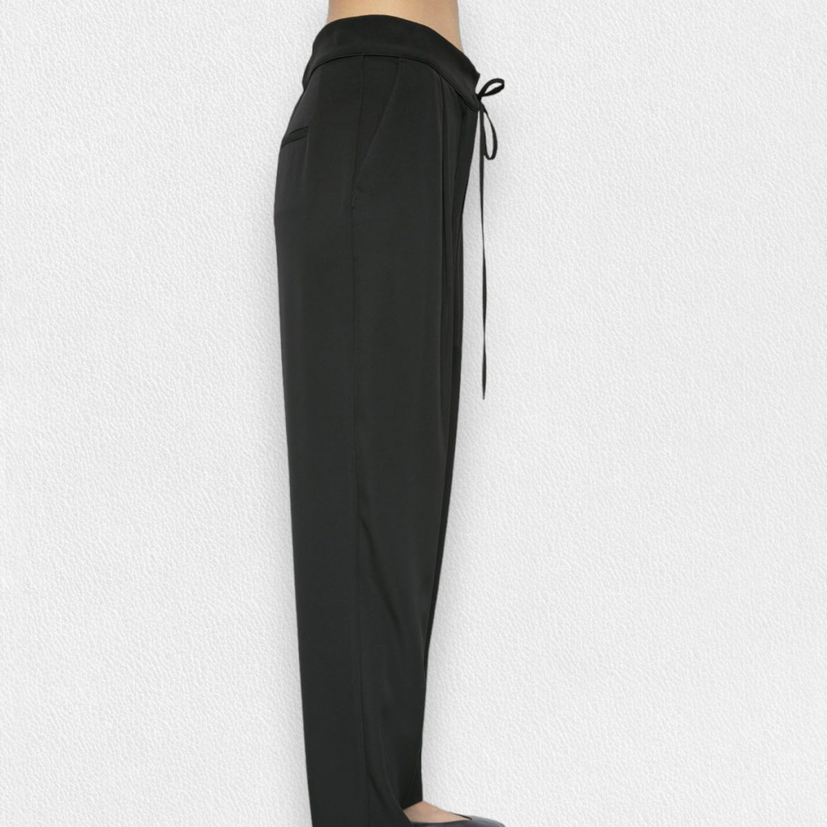 A person is wearing the MEIMEIJ - DRAWSTRING TROUSER PANT from the brand MEIMEIJ. These black, high-waisted trousers feature a loose fit and are made from a blend of polyester and elastane, complete with a tie belt. The image is taken from the waist down, showcasing the trousers in full against a plain white background, with the person&#39;s feet partially visible at the bottom.