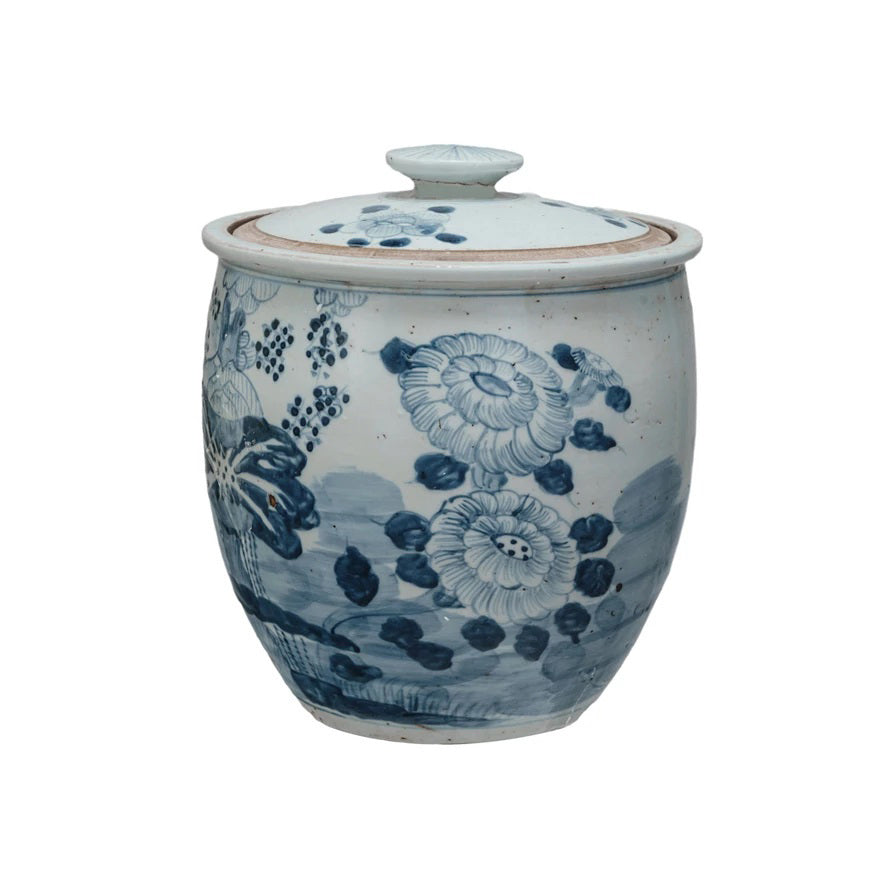 Displayed in front of a large framed Lotus Flowers print are three pieces of patterned ceramic pottery. A lidded jar and bowl feature a blue and white palette, while the PORCELAIN HANDPAINTED VINTAGE REPRODUCTION GINGER JAR from CREATIVE COOP to the right has a brown tree motif and holds a branch with sparse twigs.