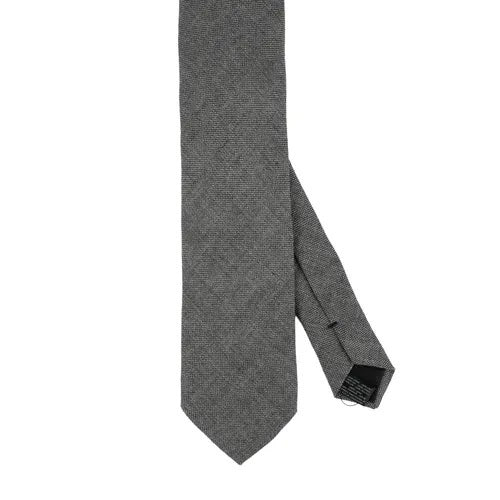 Close-up of the AMANDA CHRISTENSEN - JACQUARD LINEN TIE IN GREY, featuring a textured jacquard linen fabric in grey and a black label that reads “Amanda Christensen, Sweden 1885.” Displayed flat to reveal both the front and back, this elegant tie is a timeless staple from AMANDA CHRISTENSEN’s classic men’s accessories collection.