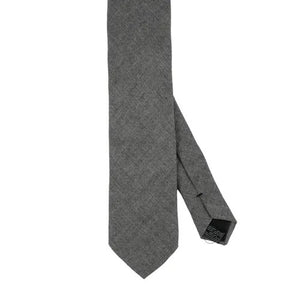 Close-up of the AMANDA CHRISTENSEN - JACQUARD LINEN TIE IN GREY, featuring a textured jacquard linen fabric in grey and a black label that reads “Amanda Christensen, Sweden 1885.” Displayed flat to reveal both the front and back, this elegant tie is a timeless staple from AMANDA CHRISTENSEN’s classic men’s accessories collection.