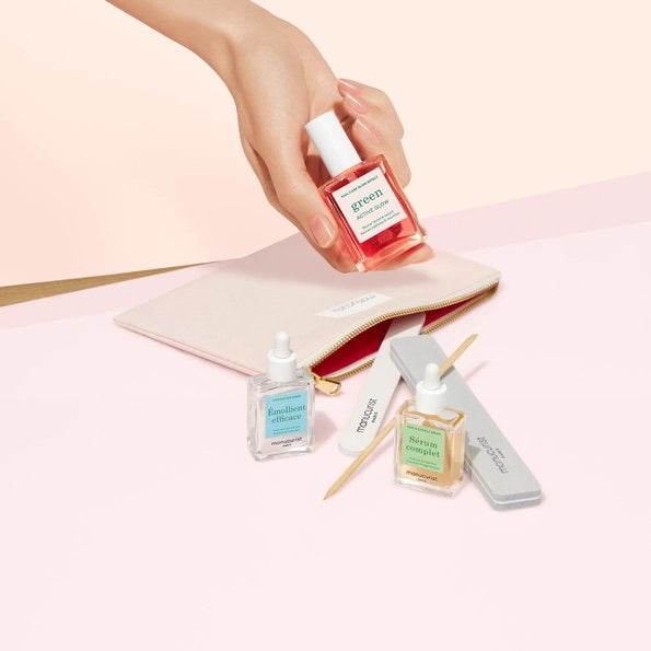 The MANUCURIST - GLOW MANICURE SET by MANUCURIST INC features a pastel pink zippered pouch, two nail files, and three bottles of vegan nail polish, all elegantly displayed on a light beige background.