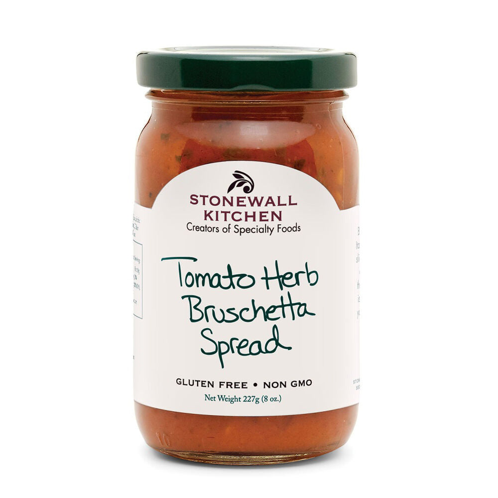 A jar of STONEWALL KITCHEN - TOMATO HERB BRUSCHETTA SPREAD, featuring a green lid, proudly displays the phrases "Creators of Specialty Foods," "Gluten Free," and "Non GMO" on its label. This bright red spread is infused with flavorful herbs and juicy tomatoes, providing a delightful blend in every 227g (8 oz) jar.