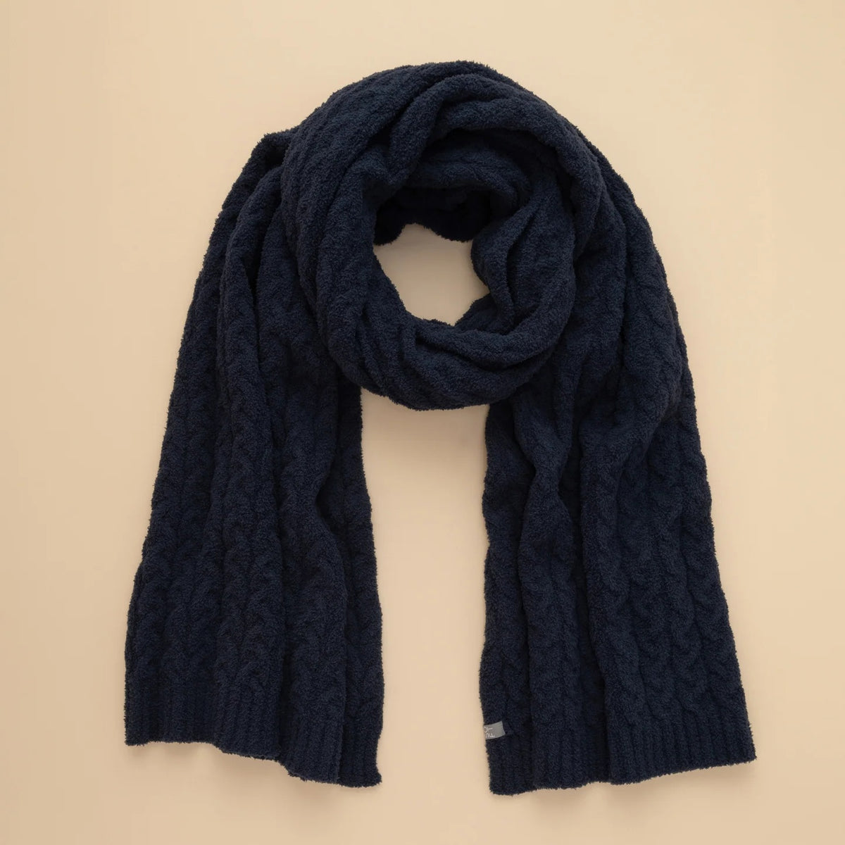 A dark navy blue SOFTIES - CABLE KNIT MARSHMALLOW SCARF draped in a loop.