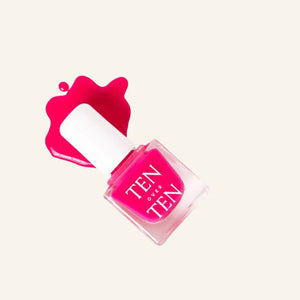 A glass bottle of TENOVERTEN - NAIL POLISH from the brand TEN OVER TEN, featuring a white cap and a dusty pink nail color. The front label displays "TEN OVER TEN" in white uppercase letters. This vegan, eight-free formula ensures both beauty and peace of mind. The background is plain and light-colored.