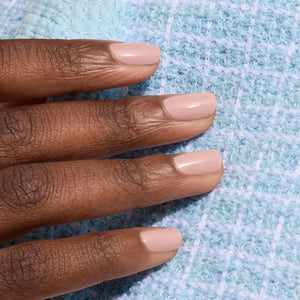 A bottle of MANUCURIST INC’s GREEN™ Nail Polish in Shell Beige, presented in a square glass bottle with a black cap and a white label displaying green and beige text. This non-toxic pinky beige polish combines elegant color with a clean, vegan formula.