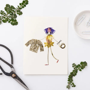 The PETAL PEOPLE PRESS - KNIT AND PURL GREETING CARD features a whimsical figure made from flower petals and leaves, with blue petal hair, a leafy jacket, and swirls of grass on a plain white background.