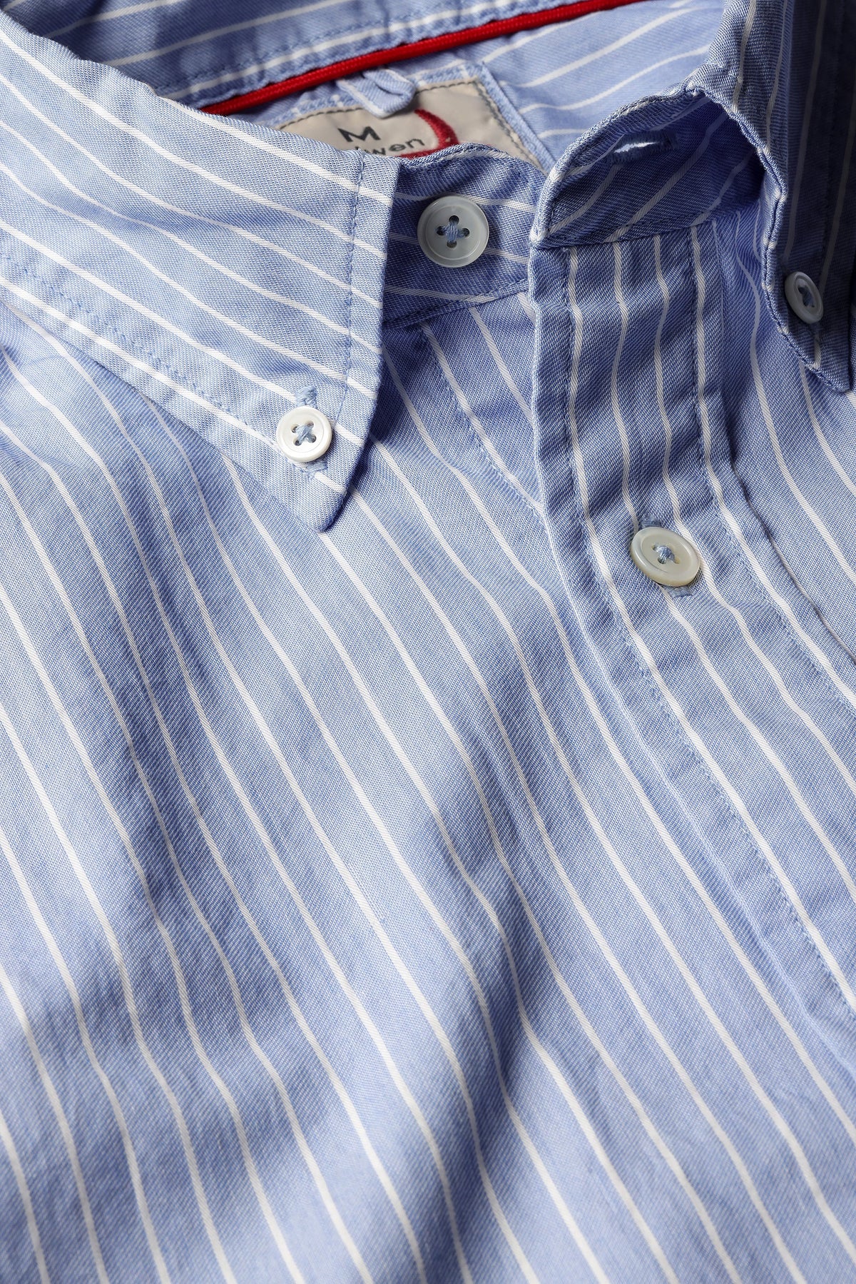 A close-up of the RELWEN - Dress Blues Shirt in Blue with White Stripe Twill by RELWEN, showcasing its light blue 100% cotton twill fabric with fine white stripes, white buttons, a classic collar, and detailed stitching that highlights the quality craftsmanship.