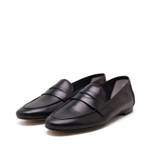 A single MICHELE LOPRIORE - PAOLA LOAFER in black is displayed against a plain white background. The shoe features a sleek and minimal design with genuine leather, a low heel, and a classic penny strap across the top, exuding an understated moccasin style by MICHELE LOPRIORE.