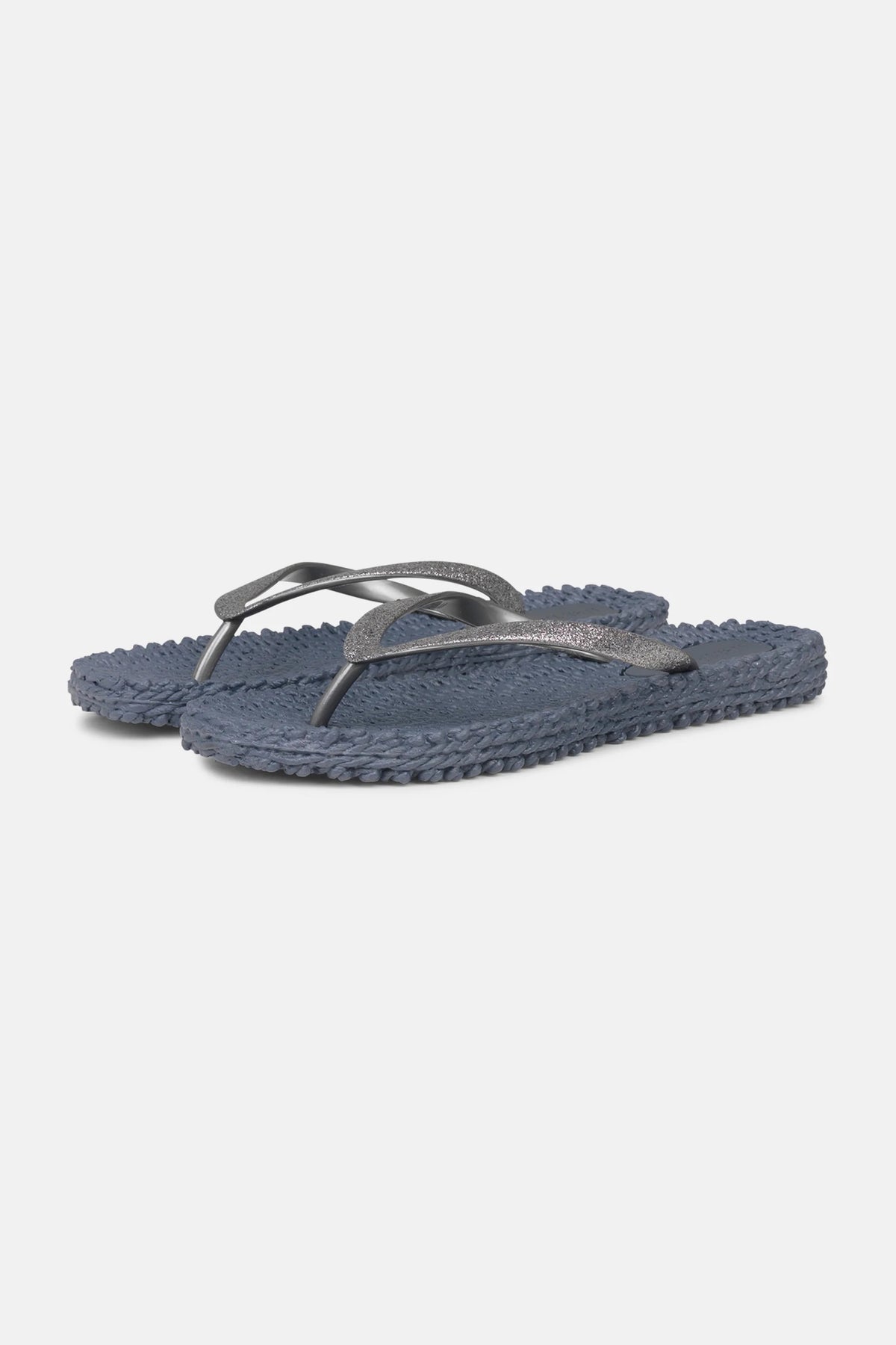 A pair of &quot;CHEERFULL Flip Flops in Grey&quot; by Lines of Denmark, featuring textured soles with dark blue straps, a slight shimmer, and a woven design on the footbed for enhanced comfort, are displayed against a plain white background.