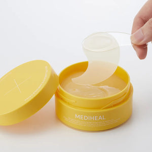 Two crescent-shaped, translucent eye patches from EXOD INTERNATIONAL's MEDIHEAL - VITA COLLAGEN EYE AMPOULE PATCH rest on a white surface. Their light peach hue evokes a yin-yang harmony while infused collagen gently reduces eye wrinkles.