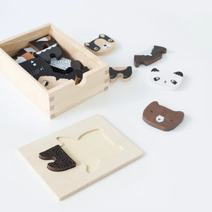 A wooden toy set titled "WEE GALLERY - MIX & MATCH ANIMAL TILES" by WEE GALLERY shown on a white background. The visible toy piece features a cartoonish animal, combining traits of a fox and a bear, painted in brown, white, and black colors. Perfect for creative play and developing motor skills, the toy is presented in a wooden box.