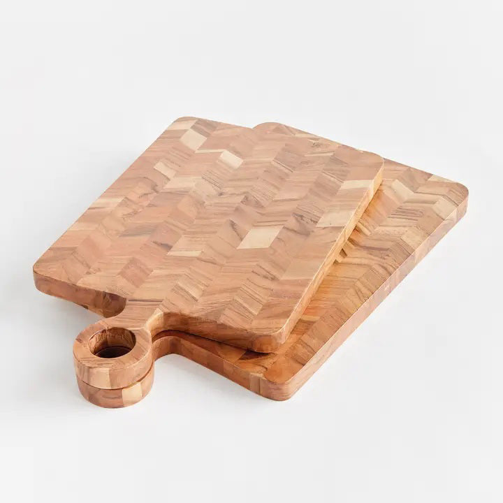 Close-up of the NAPA HOME AND GARDEN RENATA SERVING BOARD, featuring acacia wood in a chevron pattern with natural grain and light brown tones—ideal for an elegant charcuterie presentation.