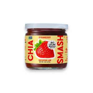 A jar of CHIA SMASH - STRAWBERRY CHIA JAM with zero added sugar. The jar boasts a red lid and a label showcasing a large strawberry illustration, along with the text "No Sugar Added!" and "Non-GMO Project Verified" certification. Made from upcycled fruit, this 8 oz (227g) jam is both paleo and vegan friendly.