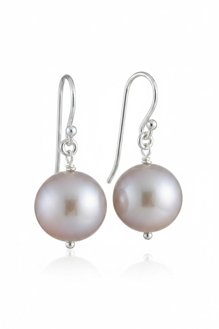 ANN LIGHTFOOT FRESHWATER PEARL DROP EARRINGS feature a single round white freshwater pearl on sterling silver earwires, shown hanging from a dark rod against a white background.