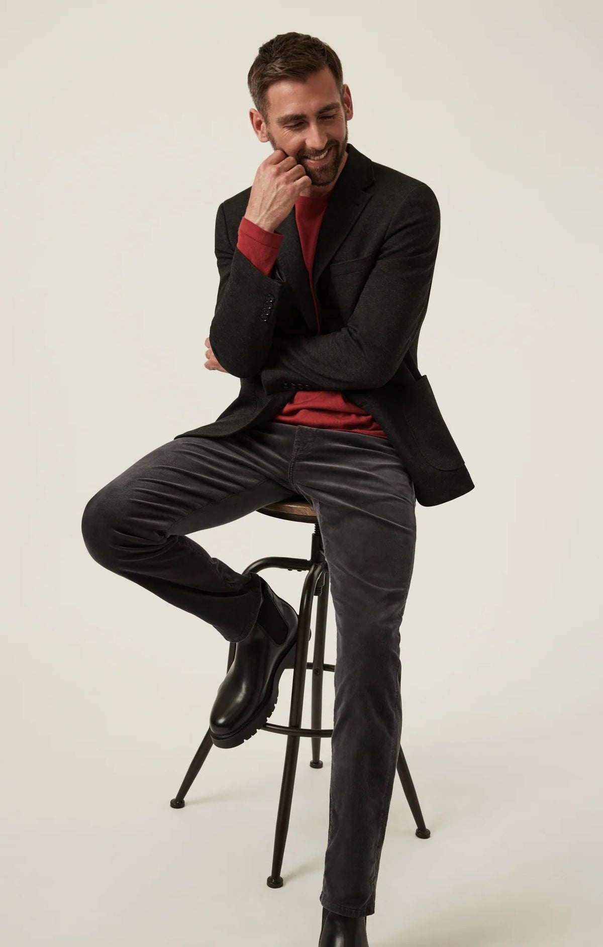34 HERITAGE - CHARISMA RELAXED STRAIGHT LEG CORDUROY PANTS IN CHARCOAL worn with a red long-sleeve shirt and black leather boots.