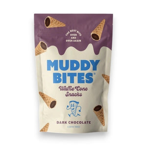 A chocolate-filled waffle cone, MUDDY BITES- DARK CHOCOLATE WAFFLE CONES, is centered against a purple background. Text reads "Creamy Dark Chocolate: Premium delicious dark chocolate made from simple ingredients" with an arrow pointing to the chocolate and "Crunchy Cone: Light crisp cone that blends perfectly with our creamy dark chocolate" with an arrow pointing to the cone. Logos for "GMO Free" and Kosher certification are at