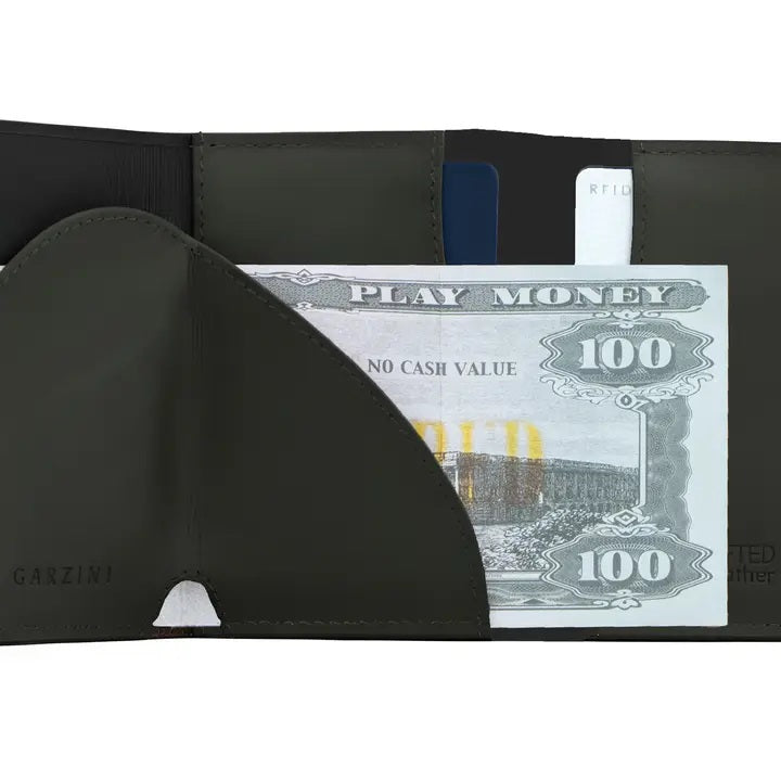 A GARZINI Slim Trifold RFID-blocking leather wallet in carbon black is shown closed, featuring a minimalist design, metal card holder, coin pocket, and the "GARZINI" logo on the side.