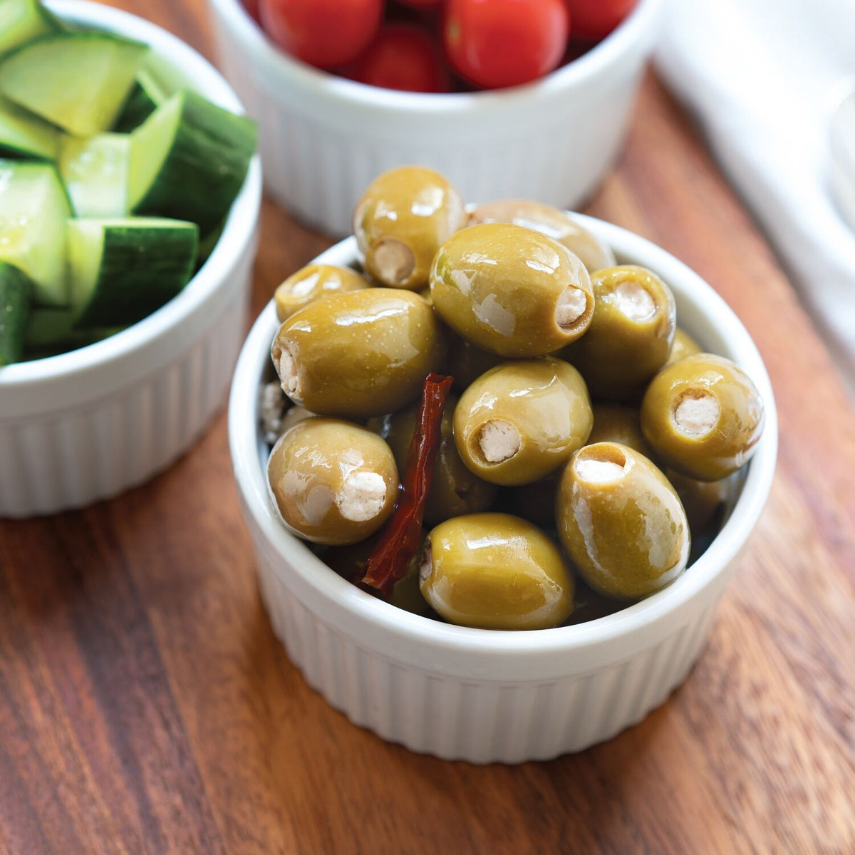 A jar of DIVINA - FETA STUFFED OLIVES by DIVINA, showcasing plump green Halkidiki olives filled with creamy feta cheese in brine. The clear glass jar reveals the olives inside and is accented with a blue and white front label. Product of Greece.