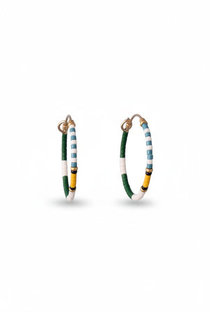 The ALICE RISE MIDI COLORLOOP EARRINGS IN FAIRWAY GREEN feature round 14k gold filled hoops with green, white, yellow, and black Japanese glass beads, displayed on a textured light blue background.