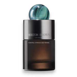 A bottle of MOLTON BROWN - COASTAL CYPRESS EAU DE PARFUM features an ocean-inspired scent, a gradient dark glass base, silver cap, and round blue-green marble-like top, displayed against a white background.