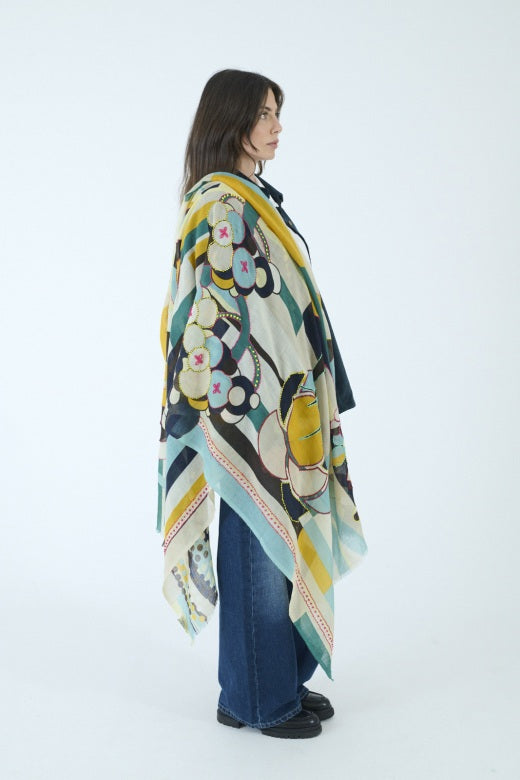 Introducing the STORIATIPIC - BAO Wool Scarf with Embroidery in Blue by STORIATIPIC: a generously sized (100 x 200 cm) wool scarf featuring a modern geometric pattern in teal, mustard yellow, brown, black, and white. Adorned with embroidered circles, dots, and rectangular motifs for a soft texture, this lightweight accessory is finished with frayed edges for added style.