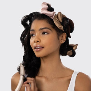 Six satin-wrapped flexi rods from KITSCH are displayed on a light background in brown and pink, with some coiled and others straight—ideal for achieving effortless, heatless curls using this vegan hair roller set.