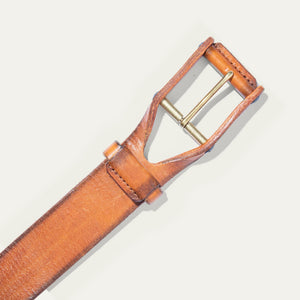 A close-up of the WILL LEATHER GOODS - LEATHER BUCKLE BELT by WILL LEATHER GOODS, featuring brown full-grain leather with a natural texture and slightly worn look, plus a gold metal buckle, displayed diagonally on a white background.