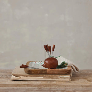 The CREATIVE COOP WOOD HEDGEHOG HOLDER WITH 6 APPETIZER PICKS features a charming wooden hedgehog design with small legs and a pointed nose, holding six metal picks in its back for a fun and functional table accessory.