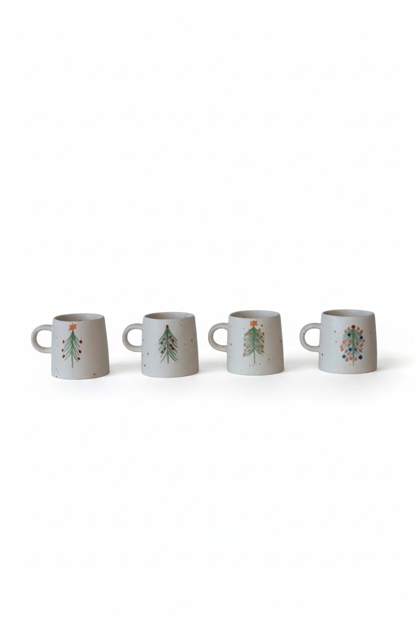 Four speckled HAND PAINTED STONEWARE MUG WITH CHRISTMAS TREE mugs by Creative Co-op lined up, each hand-painted with a unique holiday design.