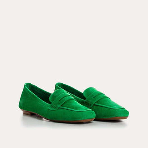A person stands on a light floor wearing blue jeans and REQINS - HEMA SUEDE LOAFER IN GAZON GREEN by REQINS, featuring a leather insole.