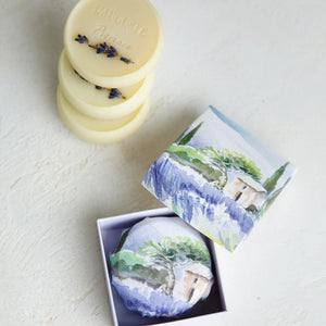 L'AUGUSTE PROVENCE's THE ESSENCE OF PROVENCE Lavender Soap with Gift Box, featuring handmade French soap and organic lavender soap in illustrated wrapping, is displayed on white fabric with dried lavender and a lavender bouquet nearby.