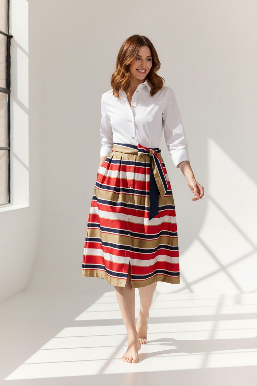 A woman stands against a plain background wearing the HINSON WU ROBIN 3/4 Sleeve Dress in Nautical Stripe, featuring red, navy, white, and tan stripes. Made from a luxurious, machine-washable cotton blend satin.