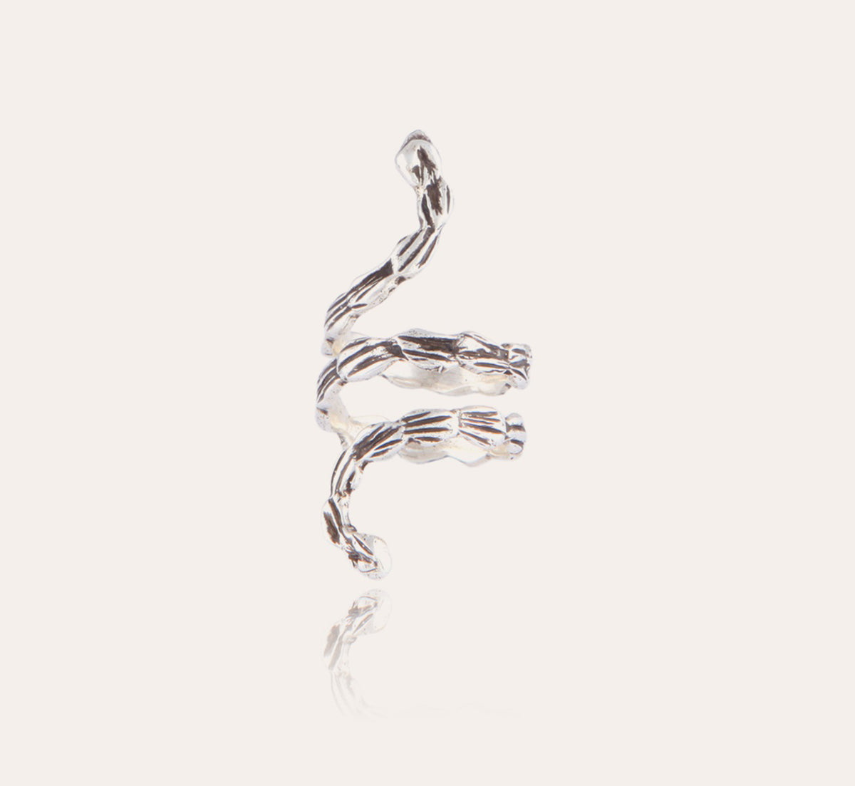 The GAS BIJOUX Liane Silver Ring features a twisted silver-plated design with abstract, flowing engravings that beautifully catch the light against a simple, off-white backdrop. This intricately crafted piece from GAS BIJOUX exudes elegance and artistry, captivating with its sense of fluidity.
