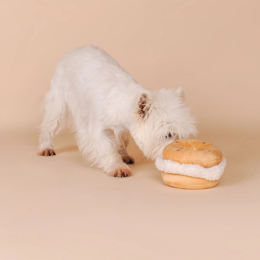 The CHEWFFON BAGEL PLUSH SQUEAKY DOG TOY is an adorable interactive plush shaped like a bagel sandwich filled with cream cheese and topped with colorful sprinkles to resemble real bagel toppings—perfect for playful pups who love a squeaky challenge!.