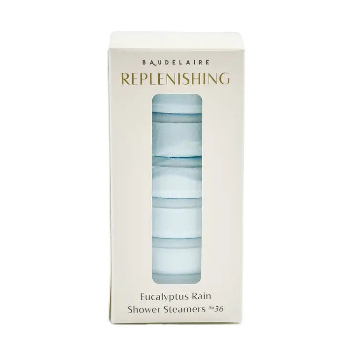 A white box labeled “BAUDELAIRE - REPLENISH EUCALYPTUS RAIN SHOWER STEAMER” by BAUDELAIRE, featuring a window that displays stacked round blue and white shower steamers inside, provides a refreshing aromatherapy experience with the invigorating scent of eucalyptus.