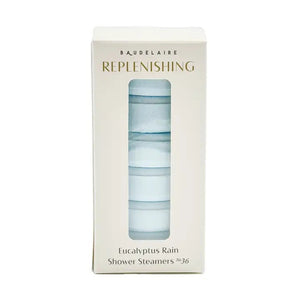 A white box labeled “BAUDELAIRE - REPLENISH EUCALYPTUS RAIN SHOWER STEAMER” by BAUDELAIRE, featuring a window that displays stacked round blue and white shower steamers inside, provides a refreshing aromatherapy experience with the invigorating scent of eucalyptus.