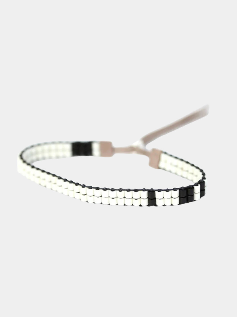 A minimalist beaded bracelet with alternating black and white square beads, shown on a light background. The bracelet has a simple adjustable closure.