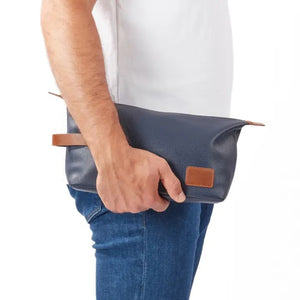 The VIENNA TOILETRY BAG IN NAVY by BEYBERK INTERNATIONAL features a rectangular navy blue leather design with brown accents, side handle, and top zipper closure, displayed on a plain white background.