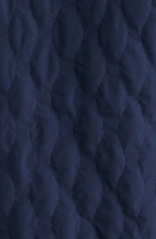 A man wears the SAVE THE DUCK Anton Jacket in navy—a dark blue, water-resistant jacket with buttoned chest pockets and a collar—paired with dark pants, standing against a plain white background.