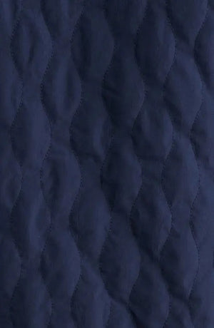 A man wears the SAVE THE DUCK Anton Jacket in navy—a dark blue, water-resistant jacket with buttoned chest pockets and a collar—paired with dark pants, standing against a plain white background.