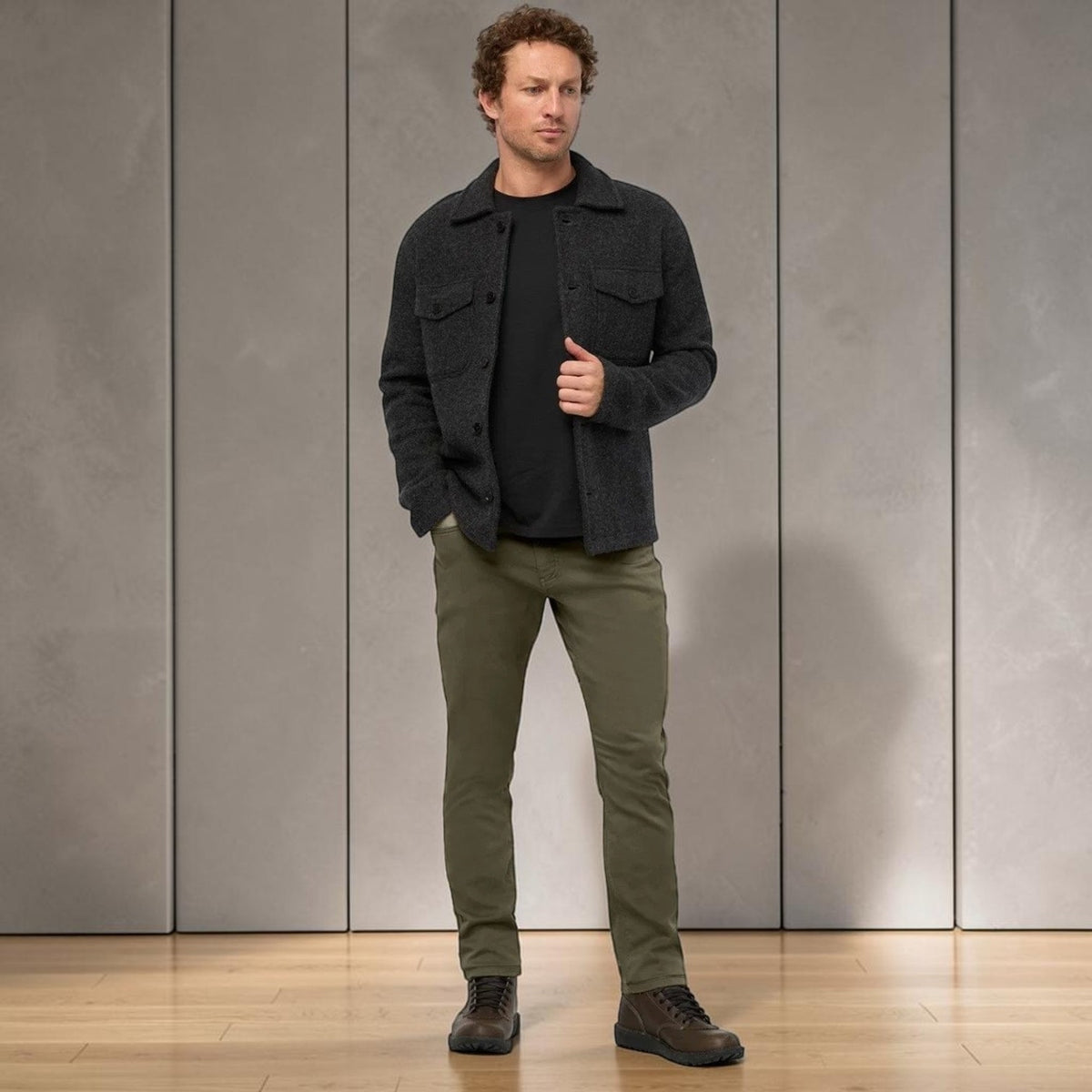 A person stands facing away from the camera against a plain background, wearing DUER - NO SWEAT ATHLETIC TAPER PANTS IN KELP paired with brown shoes.